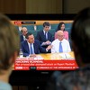 A family in Stockport, England, watch a television showing News Corporation Chief Rupert Murdoch and his son James testifying before Parliament.